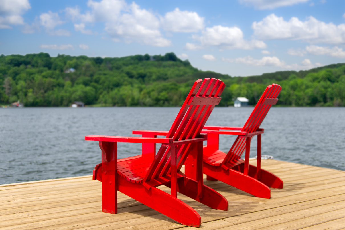 Red Muskoka chairs on a wooden dock